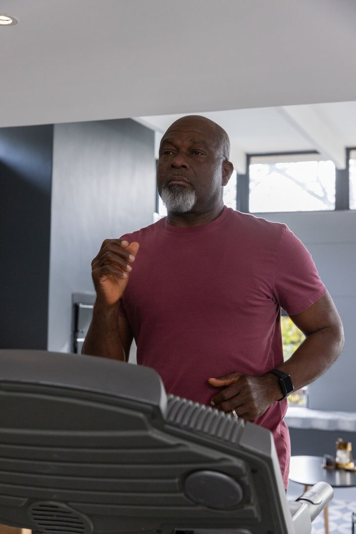 Senior Man Running on Treadmill in Home Gym with Smartwatch