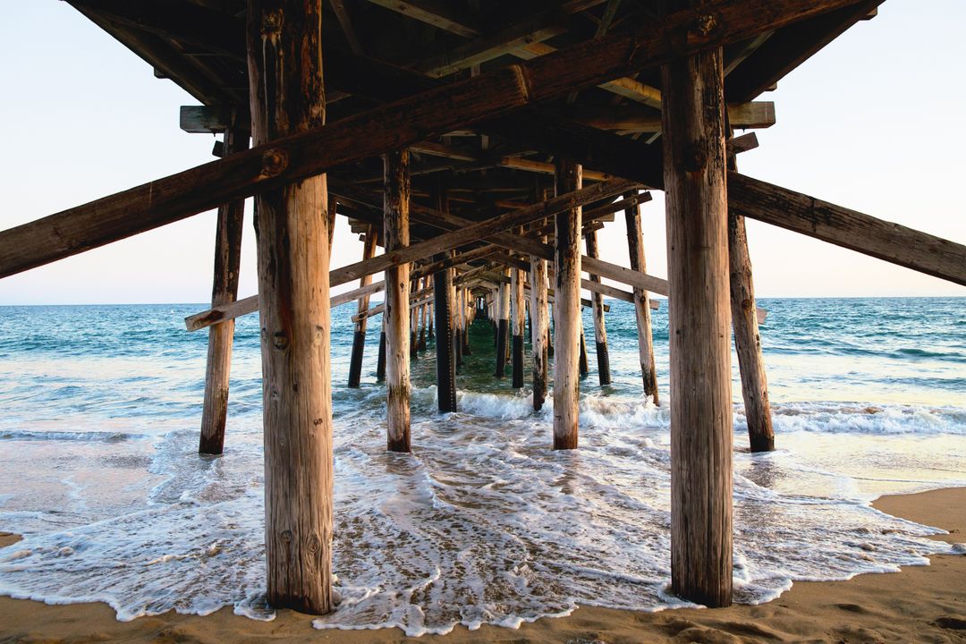 Sunset View Under Wooden Pier With Ocean Waves Hitting Shore - Free Images, Stock Photos and Pictures on Pikwizard.com