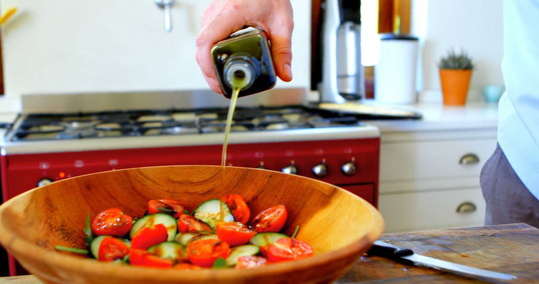 Man Pouring Olive Oil on Fresh Vegetable Salad in Kitchen - Free Images, Stock Photos and Pictures on Pikwizard.com