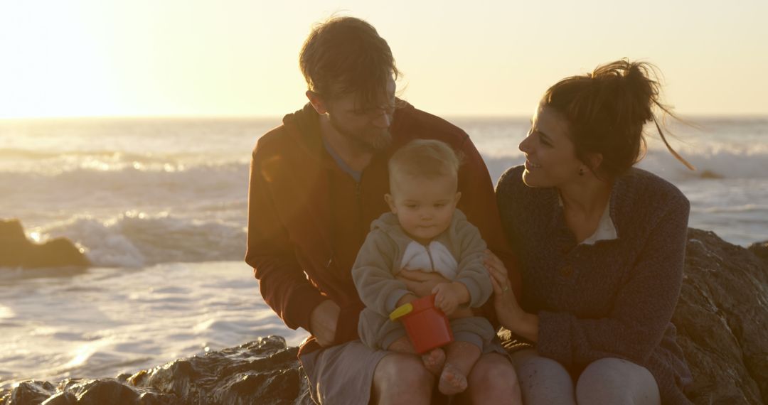 Happy Family Sitting on Rocks Near Ocean at Sunset - Free Images, Stock Photos and Pictures on Pikwizard.com