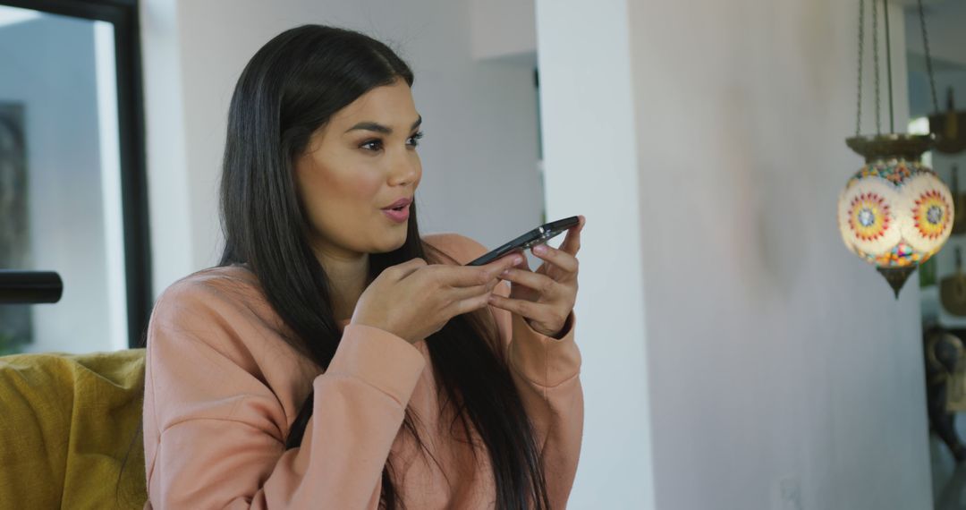 Image of happy biracial woman sitting on sofa and using smartphone - Free Images, Stock Photos and Pictures on Pikwizard.com