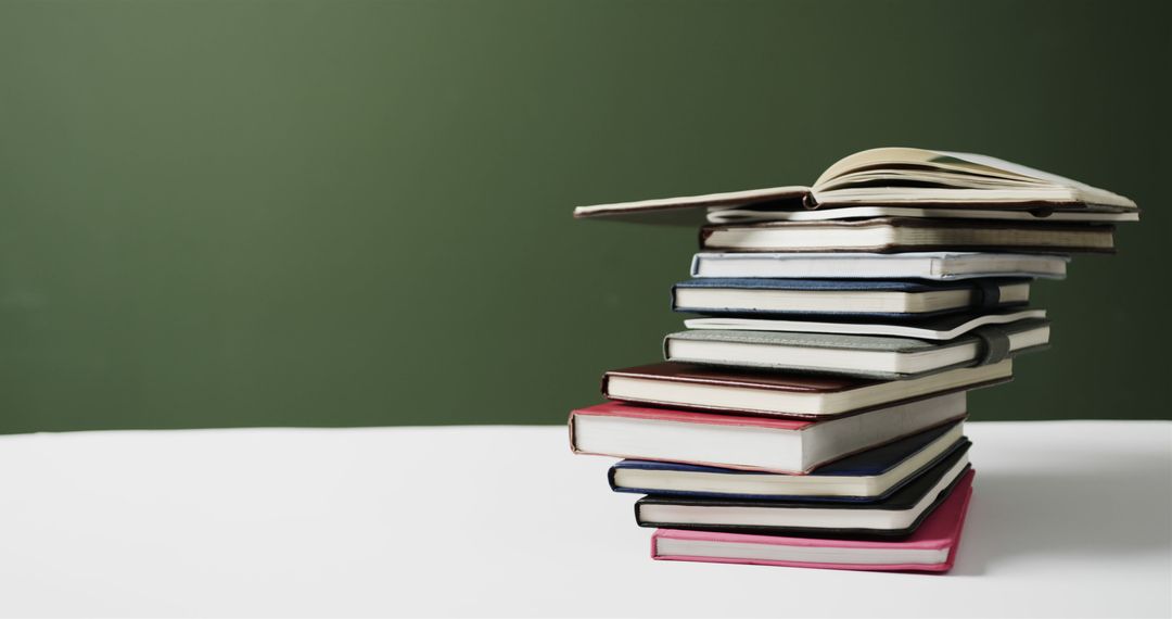 Closeup Stack of Books on White Table with Green Background - Free Images, Stock Photos and Pictures on Pikwizard.com