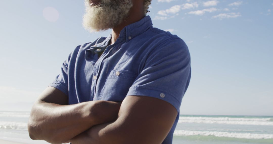 Close-up African American man standing on beach with arms crossed - Free Images, Stock Photos and Pictures on Pikwizard.com