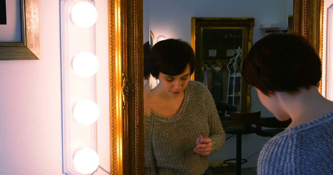 Woman Applying Makeup in Front of Vanity Mirror with Lights - Free Images, Stock Photos and Pictures on Pikwizard.com