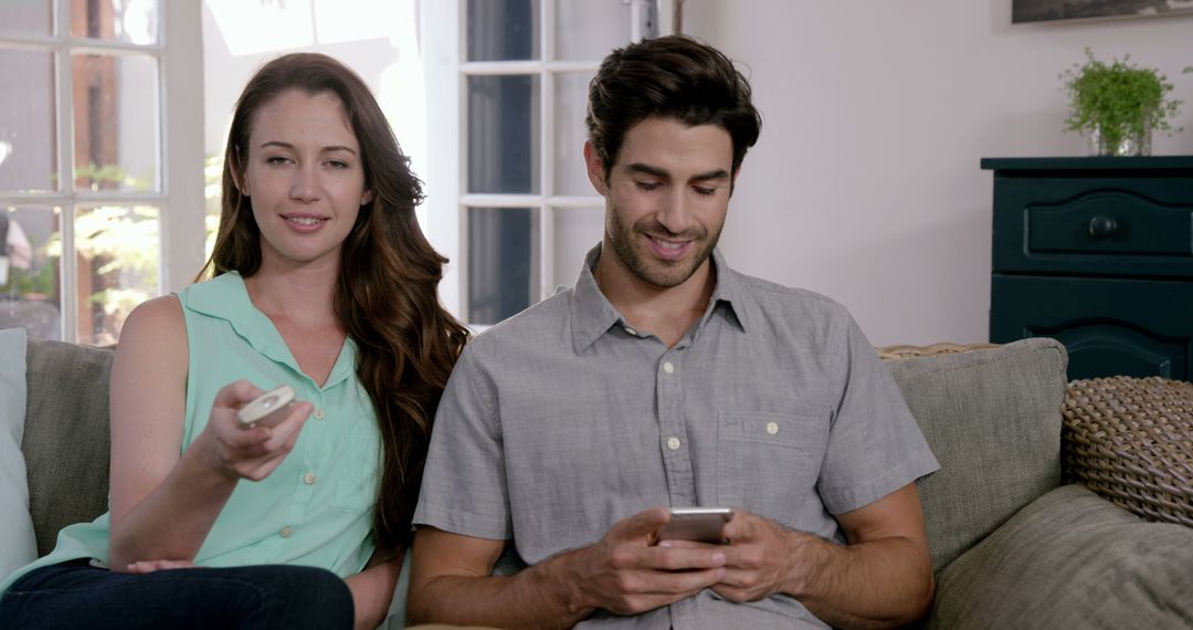 Happy Couple Relaxing on Couch with Remote in Hand
