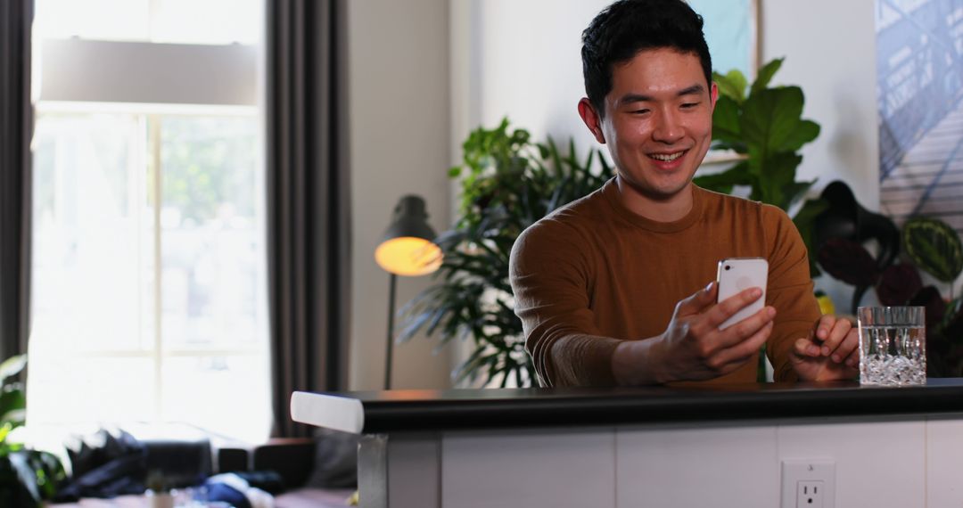 Smiling Man Using Smartphone in Modern Living Room with Plants - Free Images, Stock Photos and Pictures on Pikwizard.com