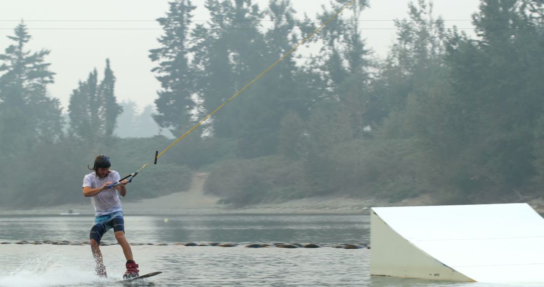 Young Man Wakeboarding on Lake in Foggy Weather - Free Images, Stock Photos and Pictures on Pikwizard.com