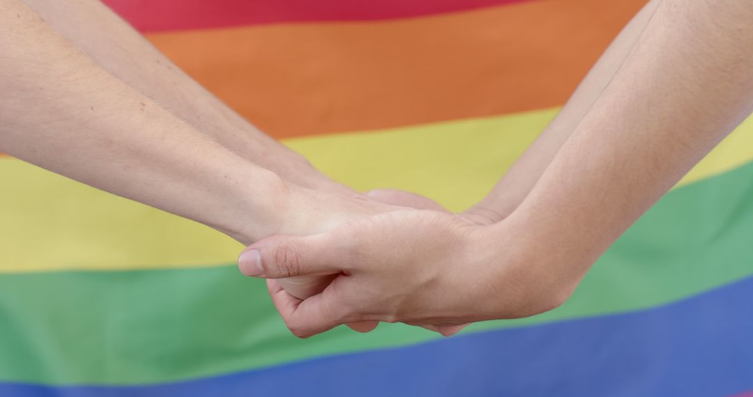 Close Up of Hands Holding with Rainbow Flag Background