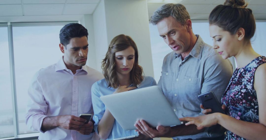 Team of Professionals Analyzing Data on Laptop in Modern Office