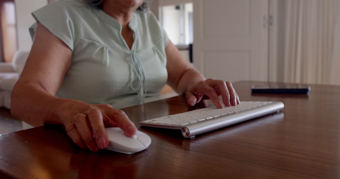 Senior Woman Typing on Wireless Keyboard in Home Office Setting