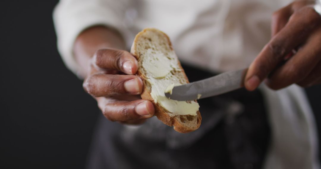 Chef Spreading Butter on Bread Slice with Knife