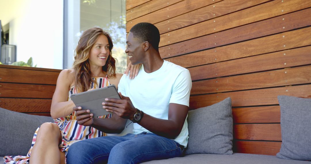 Smiling Couple Using Tablet Indoors on Cozy Couch