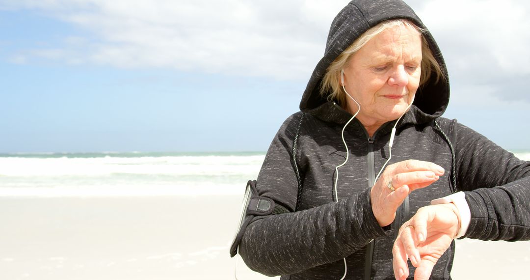 Senior Woman Checking Fitness Tracker While Exercising on Beach - Free Images, Stock Photos and Pictures on Pikwizard.com