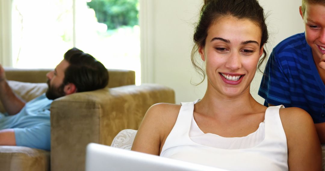 Smiling Woman Using Laptop at Home with Family - Free Images, Stock Photos and Pictures on Pikwizard.com