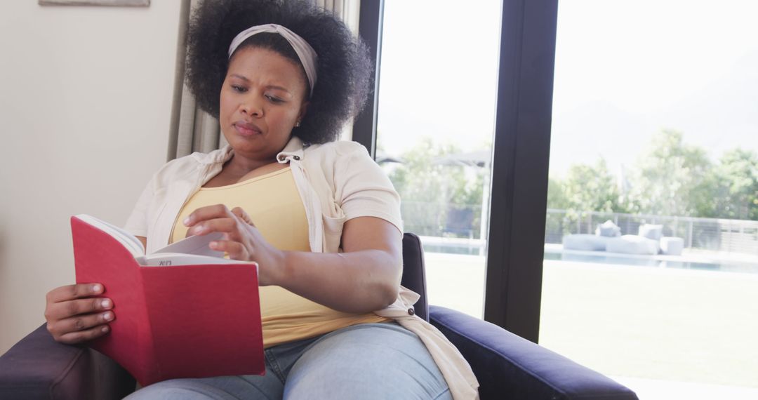 Young African American Woman Reading Book by Window - Free Images, Stock Photos and Pictures on Pikwizard.com