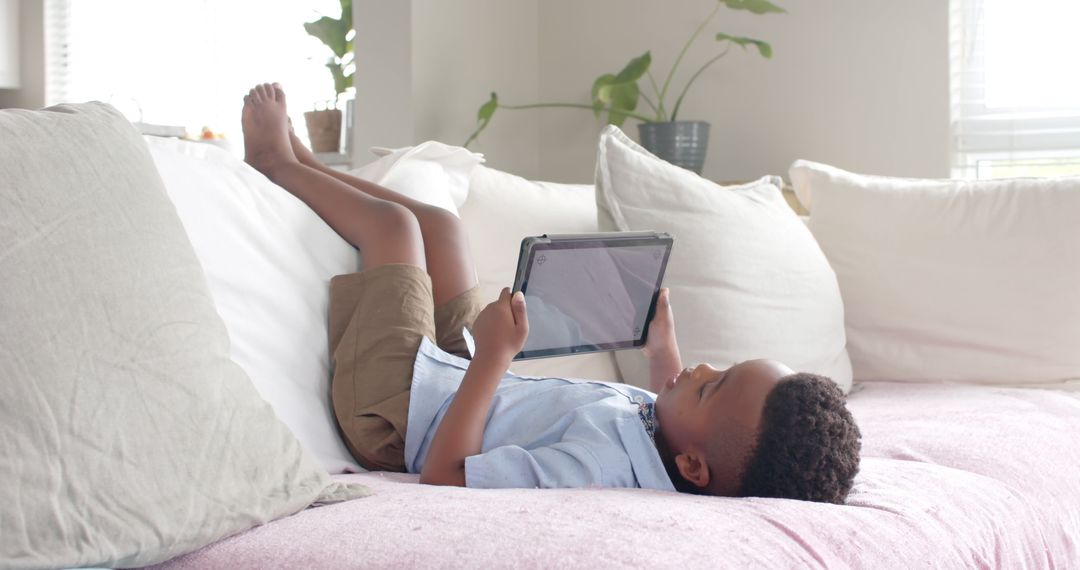 Child Relaxing on Couch with Tablet - Free Images, Stock Photos and Pictures on Pikwizard.com