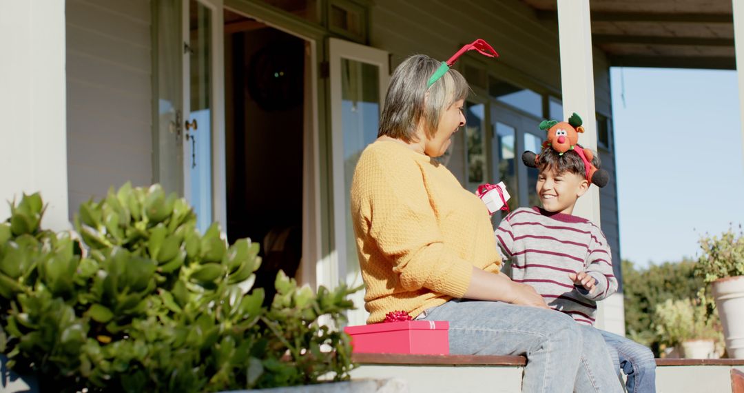 Grandmother and Grandson Exchanging Christmas Gifts on Porch - Free Images, Stock Photos and Pictures on Pikwizard.com