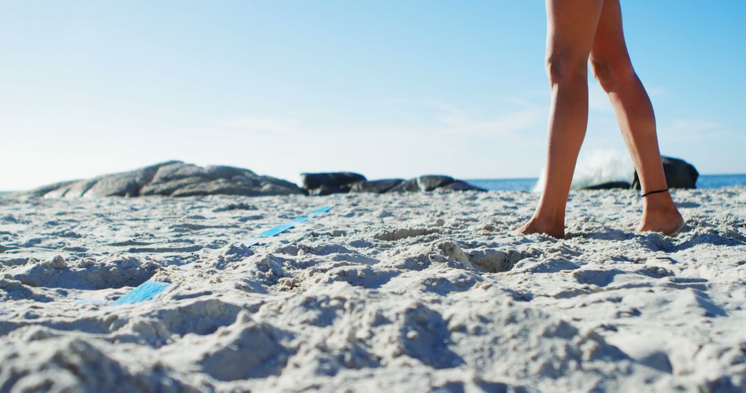 Close-Up of Person Walking on Sandy Beach with Rocky Background - Free Images, Stock Photos and Pictures on Pikwizard.com