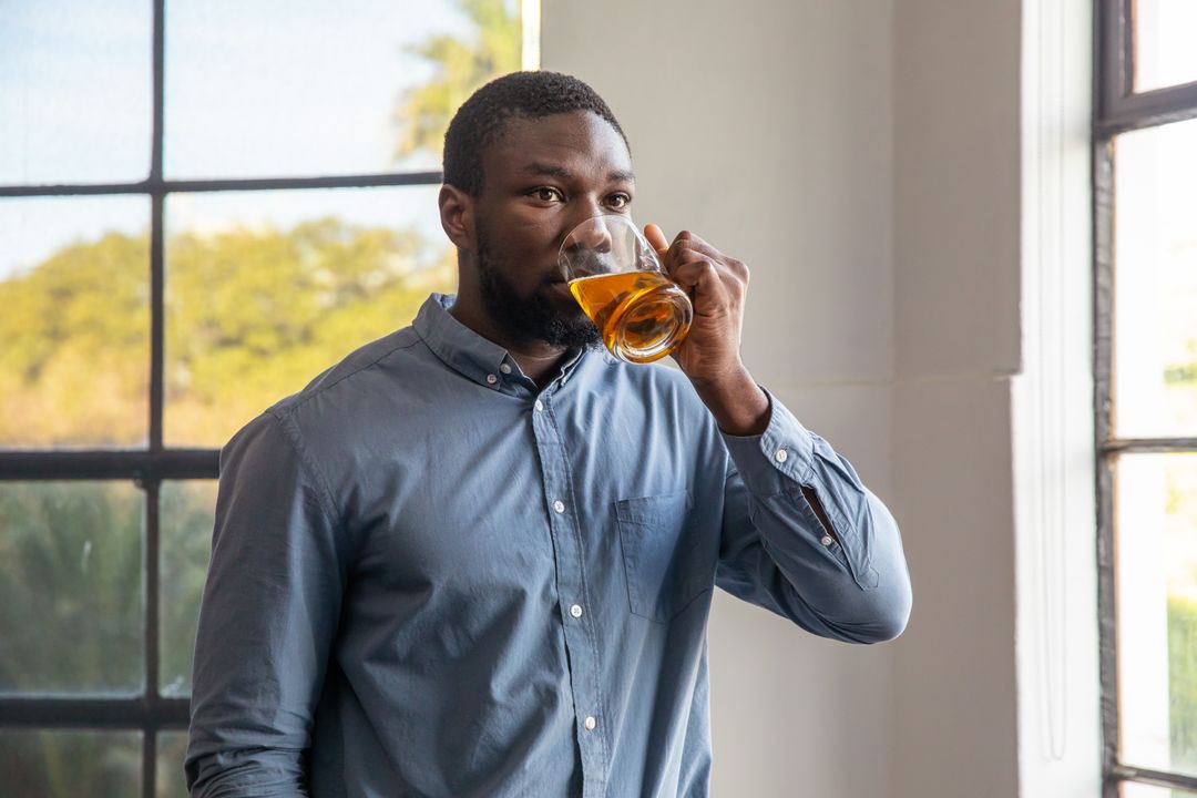 Man in Modern Lounge Enjoying Refreshing Beverage Near Window