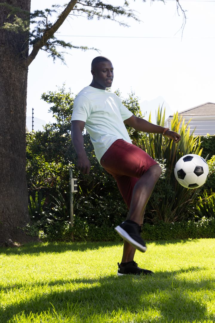 Man Practicing Soccer Skills in Sunlit Backyard