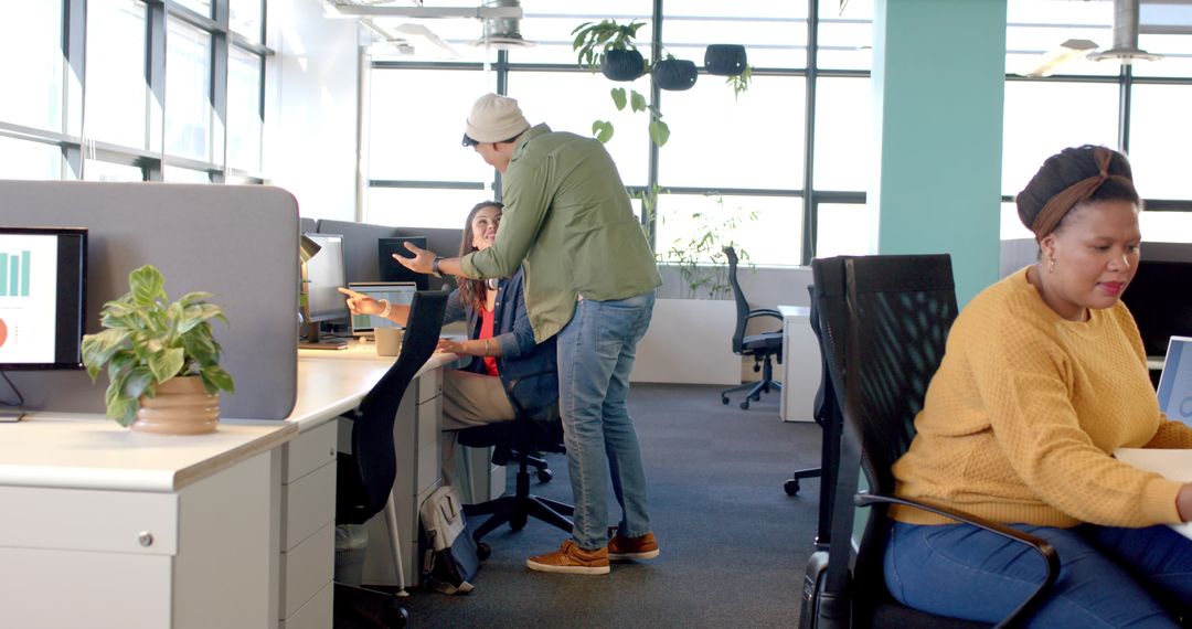 Multicultural team collaborating in bright open-plan office discussing bar chart on monitor
