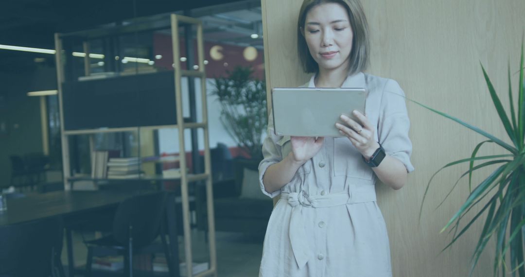 Asian Woman Using Tablet in Modern Office Setting Relaxed and Professional