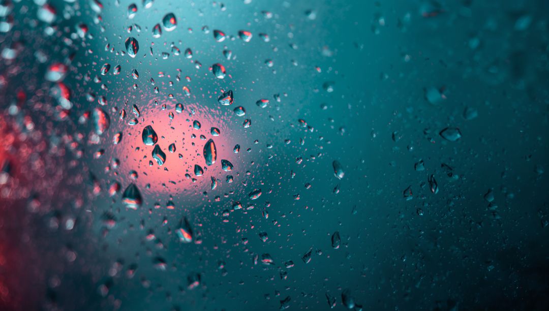 Raindrops on Glass with Blurred Lights Creating Dreamlike Effect