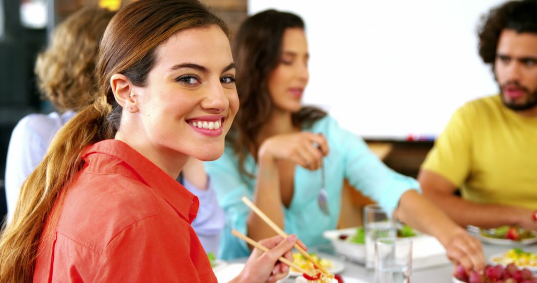 Smiling Woman Eating with Friends Using Chopsticks at Dinner - Free Images, Stock Photos and Pictures on Pikwizard.com