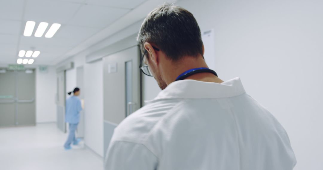 Male Doctor Walking Down Hospital Corridor - Free Images, Stock Photos and Pictures on Pikwizard.com