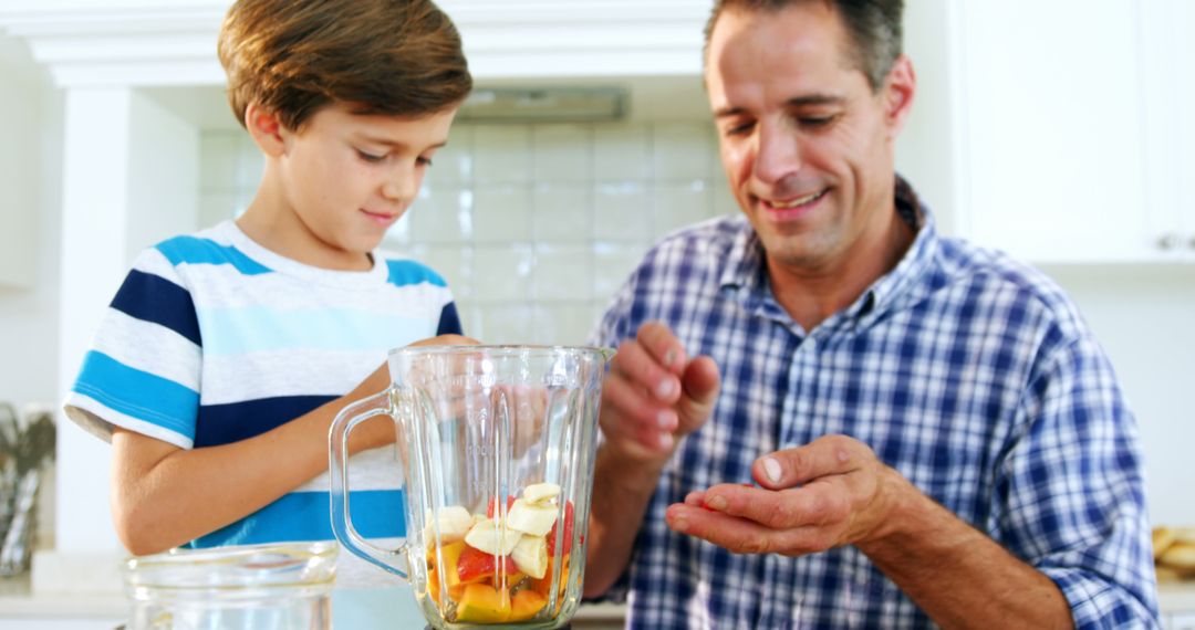 Father and son preparing healthy smoothie in kitchen - Free Images, Stock Photos and Pictures on Pikwizard.com