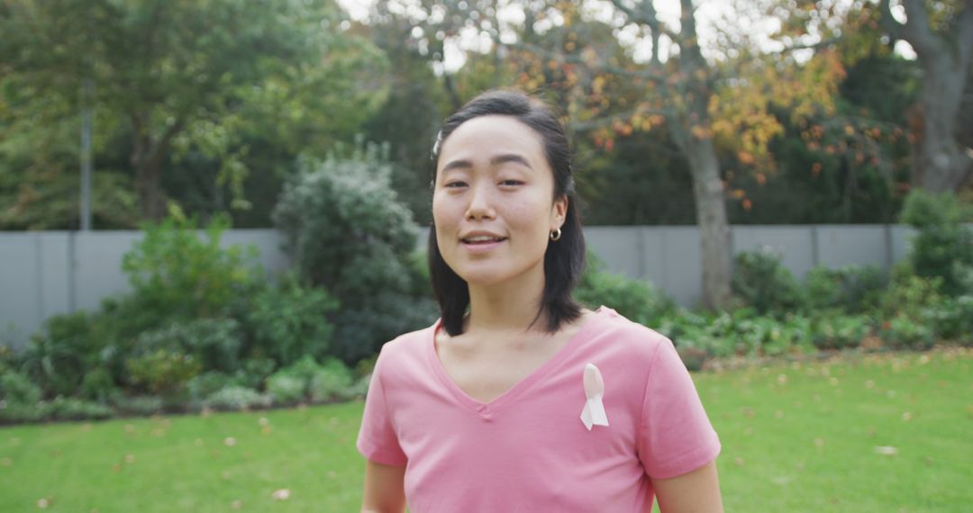 Portrait of happy asian woman wearing pink t shirt and cancer ribbon, standing in garden laughing - Free Images, Stock Photos and Pictures on Pikwizard.com