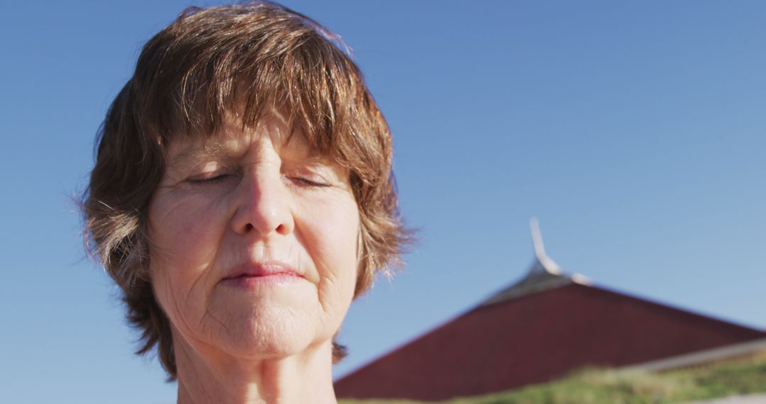 Senior Woman Meditating Outdoors with Pyramid Structure in Background - Free Images, Stock Photos and Pictures on Pikwizard.com