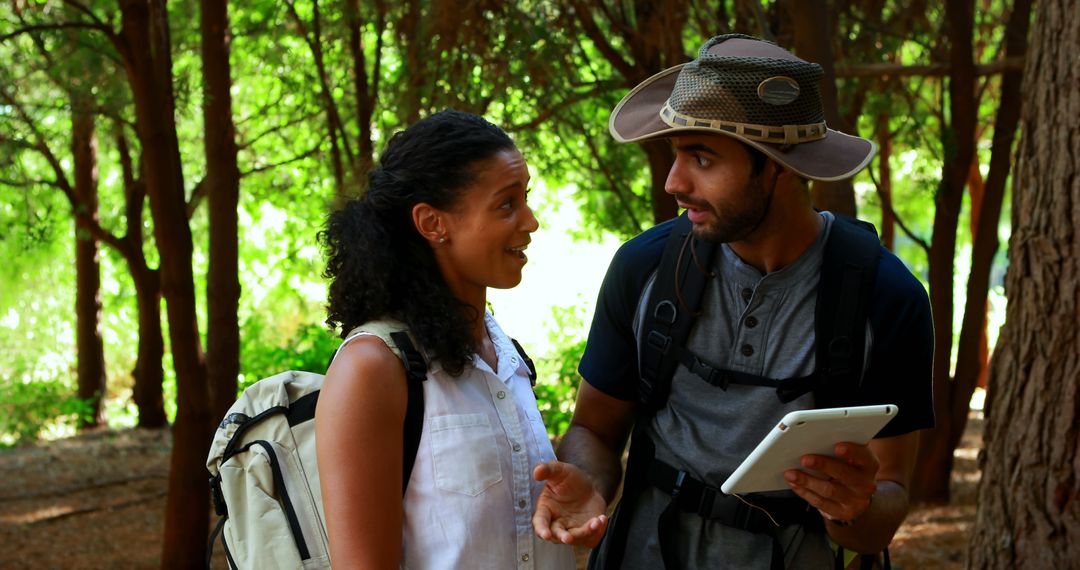Adventurous Hikers Using Tablet in Sunlit Forest