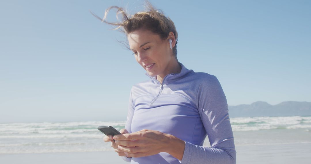 Woman Jogging on Beach Using Smartphone with Earbuds - Free Images, Stock Photos and Pictures on Pikwizard.com