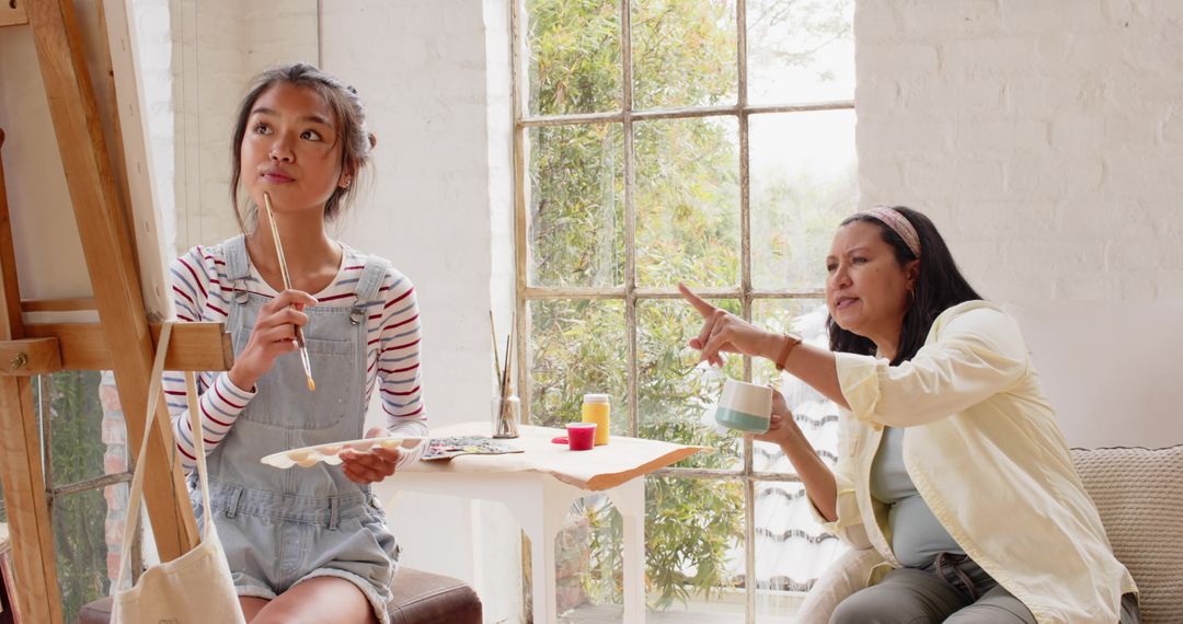 Young Artist Painting on Easel Guided by Instructor in Cozy Studio