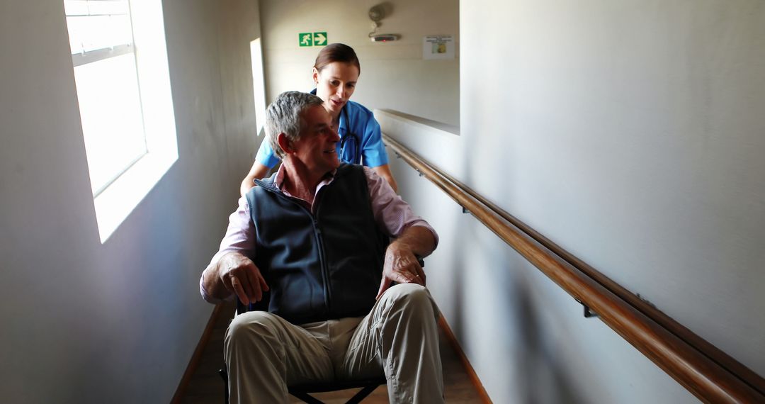 Nurse Assisting Elderly Man in Wheelchair Down Corridor - Free Images, Stock Photos and Pictures on Pikwizard.com