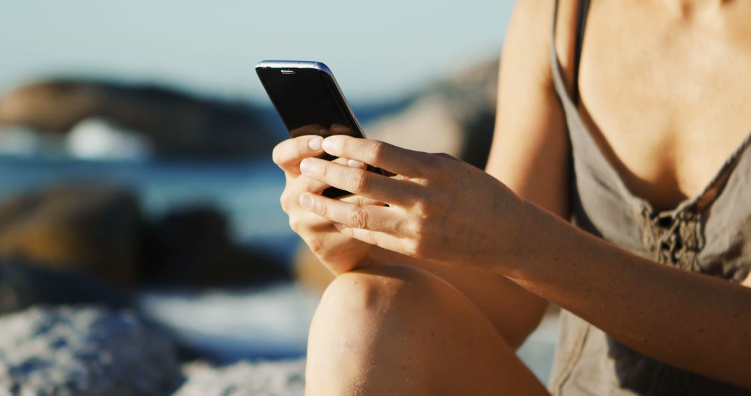 Close-Up of Woman Using Smartphone Outdoors by the Sea - Free Images, Stock Photos and Pictures on Pikwizard.com