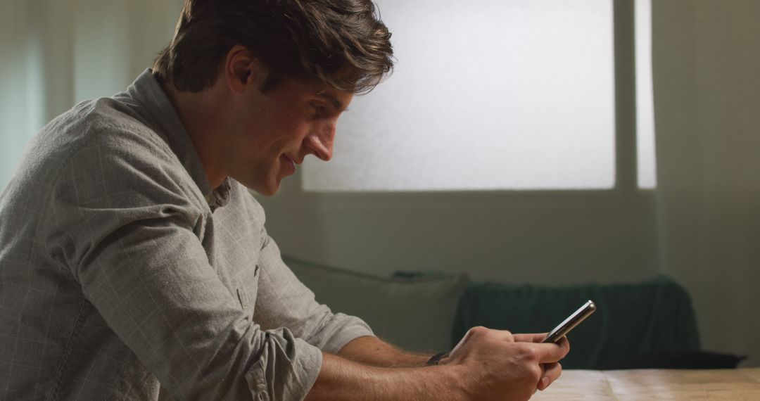 Young Man Sitting Indoors Typing on Smartphone - Free Images, Stock Photos and Pictures on Pikwizard.com