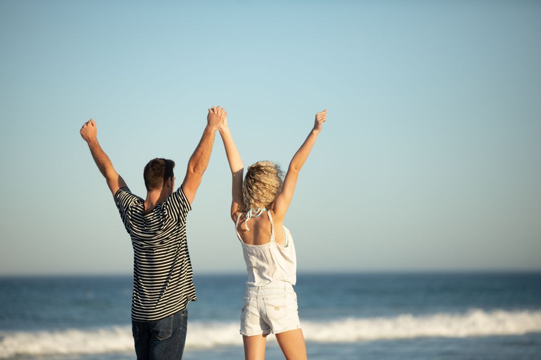 Couple Celebrating at Beach with Raised Arms - Free Images, Stock Photos and Pictures on Pikwizard.com