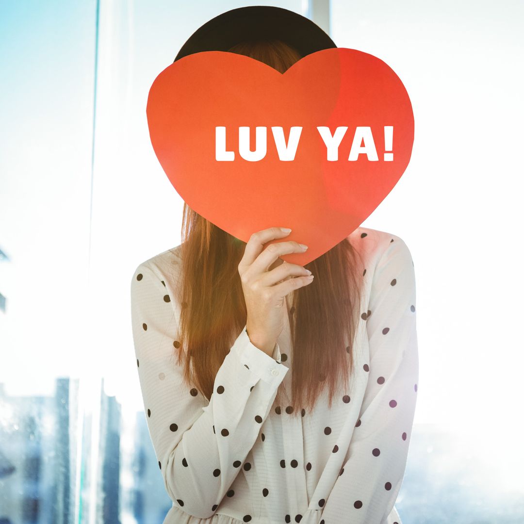 Person Holding Heart-Shaped Sign with Playful Affectionate Message