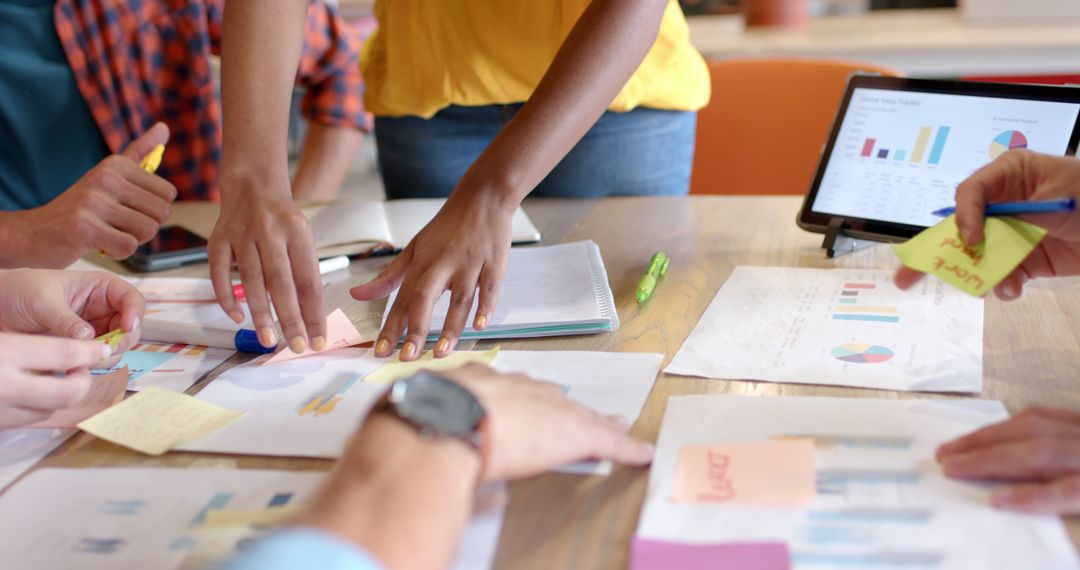 Diverse Team Collaborating on Project with Documents and Laptop in Office