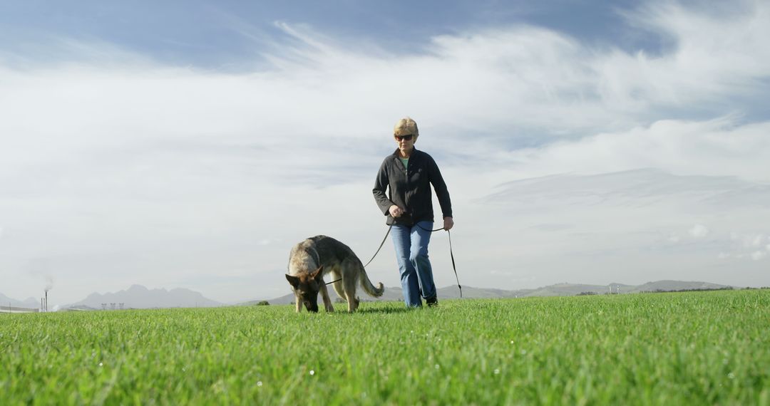 Man Walking German Shepherd Dog on Grass Field Under Blue Sky - Free Images, Stock Photos and Pictures on Pikwizard.com