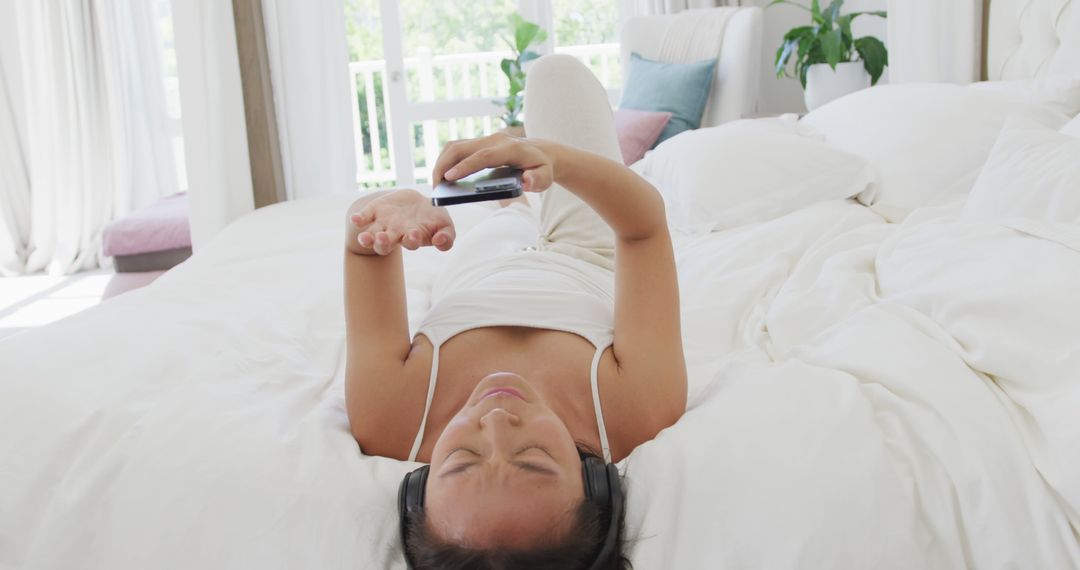 Relaxed Young Woman Listening to Music on Bed with Headphones and Smartphone - Free Images, Stock Photos and Pictures on Pikwizard.com