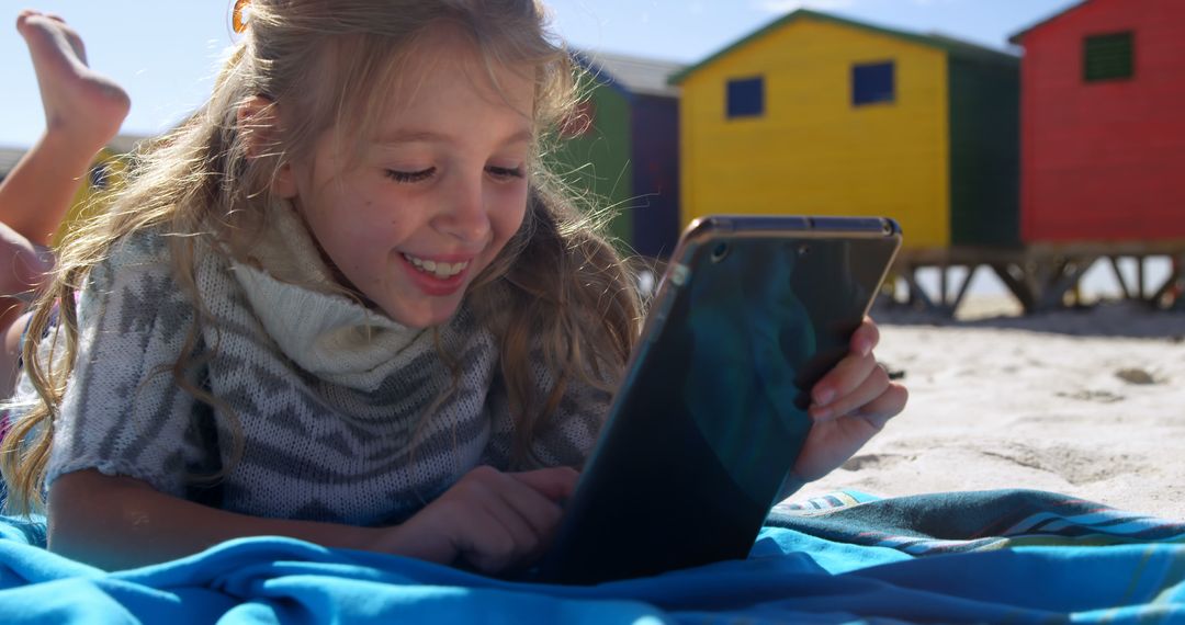 Happy Girl Using Tablet on Beach with Colorful Cabins - Free Images, Stock Photos and Pictures on Pikwizard.com