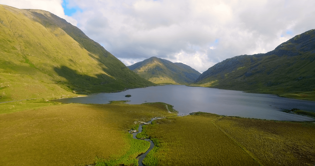 Transparent Lake Amidst Majestic Mountains under Cloudy Sky