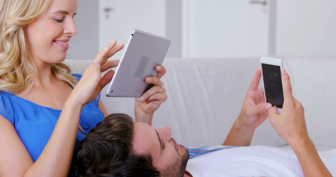 Relaxed Couple Engaging with Devices on Sofa at Home