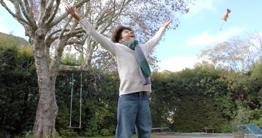 Boy Joyfully Tossing Leaves in Autumn Garden
