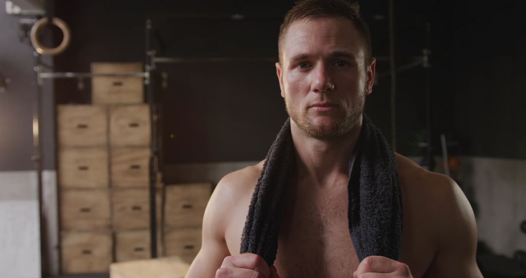 Athletic Caucasian Man Resting at Gym After Intense Workout Holding Towel