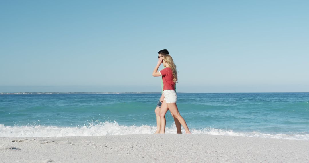 Couple Walking on Sandy Beach Against Ocean Waves on Sunny Day - Free Images, Stock Photos and Pictures on Pikwizard.com