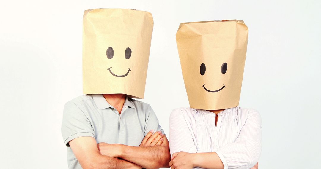 Two adults with bag-covered, smiley-drawn heads pose humorously, exuding mystery. - Free Images, Stock Photos and Pictures on Pikwizard.com